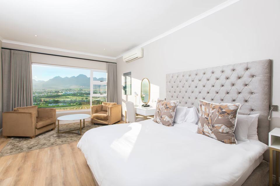 A bedroom with a large bed and a view over the vineyards.
